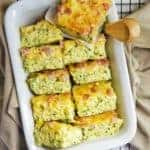 Gluten Free Zucchini Slice pieces in a white baking tray with small utensil on the side