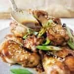 Spoon pouring sauce over honey soy chicken wings
