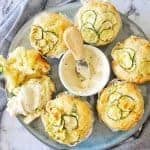Zucchini Parmesan Muffins on a blue plate with mustard yoghurt
