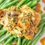 Close up shot of honey mustard chicken thighs with green beans on white plate