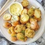 Skin on roast potatoes on a grey plate with a small white bowl with mustard