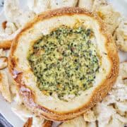 Cob loaf dip on large white plate with extra toasted bread bits.