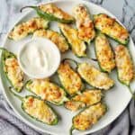 Air Fryer Stuffed Jalapenos on a white plate with dip bowl