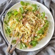 Bacon Spaghetti on a white plate with spoon and fork in the pasta