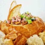 Bread pieces stick out of bacon and cheese cob loaf.