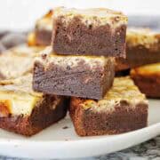 Baileys brownies cut into portions and stacked on a white plate.