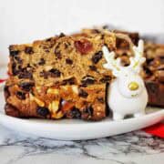 Fruit cake slices on white plate with small reindeer figure.
