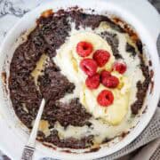 Baileys pudding in blue baking dish with cream and raspberries..