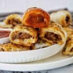 Beef Mince Sausage Rolls with top one dunked in tomato sauce on white plate