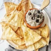 Black Olive Dip in bowl on plate with pita chips