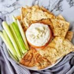 Blue Cheese Yogurt Dip with celery sticks and pita chips on white plate