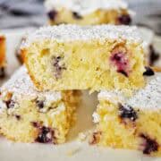 Blueberry slice cut into pieces, dusted with icing sugar and staked on a white plate.