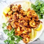 Cooked prawns with seasoning on white plate.