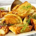 Caramelised fennel wedges on white plate with large silver spoon.