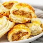 Sausage rolls stacked on white plate.