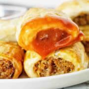 Sausage rolls with tomato sauce on white plate.