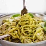 Fork being twirled in grey bowl of chicken pesto linguine.