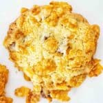 Chocolate chip cookie with cornflakes on the outside on white plate.