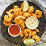Coconut panko prawns on black plate with 2 dipping sauces.