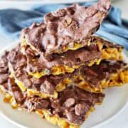 Pieces of cornflake crack stacked on a white plate.