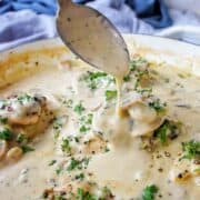 Spoon pouring creamy sauce over mushroom chicken thighs