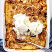 Croissant bread and butter pudding with ice cream in large white baking dish.