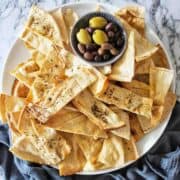 Homemade Pita Chips on a white platter with olives