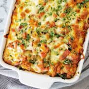 Ham and egg croissant bake in a large white baking dish with thyme leaves on top.