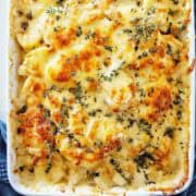 French onion potato bake topped with thyme in white baking dish.