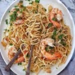 Garlic Prawn Spaghetti on a white plate with spoon and fork