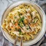 Grilled chicken alfredo in grey bowl with fork and spoon.