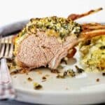 Rack of lamb on white plate with potato bake.
