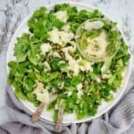 Herb Salad with capers and parmesan on a white plate