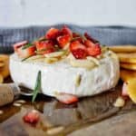 Honey Baked Camembert with strawberries and rosemary on timber board