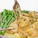 Fork being pushed into Kottbullar Swedish Meatballs with broccolini and mashed potatoes.