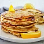Lemon pancakes on white plate with fresh lemon wedges