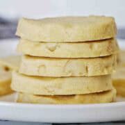A stack of 5 macadamia nut shortbread cookies on white plate.