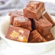 Chopped pieces of mars bar fudge stacked in white bowl.
