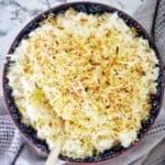 Cooked coconut rice in blue bowl with lime zest and toasted coconut on top.