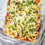 Cooked chicken enchiladas with cheese and sauce in glass baking dish.