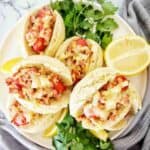 Mini hot dogs with bacon, onion and cheese on white plate.