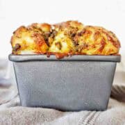 Pesto bread in bread tin with grey napkin below.