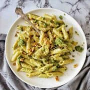 Pesto Penne on a white plate with a fork in the top left