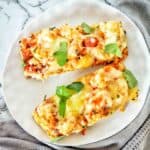 Two pizza slices on a white plate with herb garnish on top.