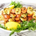Skewers with prawns and chorizo on white plate.