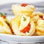 Puff pastry bites with pepper jelly and brie on white plate.