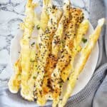 Baked cheese twists on white plate with bagel seasoning.