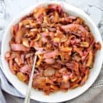 Caramelised onions in a white bowl with silver spoon.