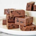 Pieces of fudge with raisins stacked on a white plate.