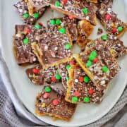 Pieces of salada christmas crack spread out on a white serving platter.